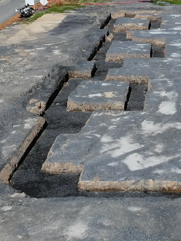Excavated foundation footings filled with aggregate.