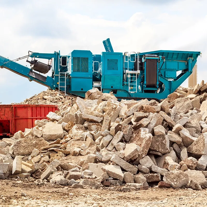 A blue concrete crushing manchine is crushing old concrete.