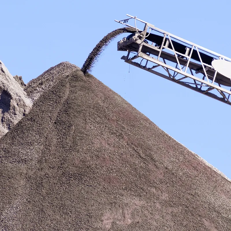 A pile of crushed asphalt being poured from a conveyor.
