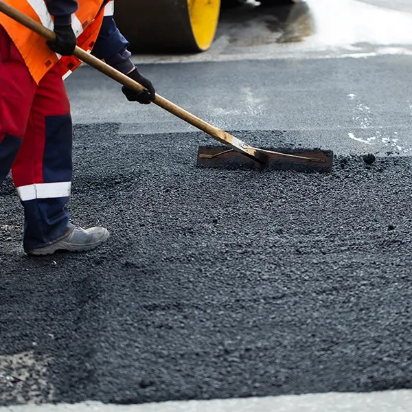 A person is sweeping asphalt.