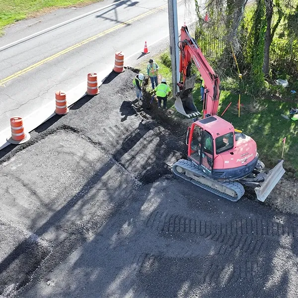 An aerial view of a construction site with workers and machinery surrounded by orange barrels.