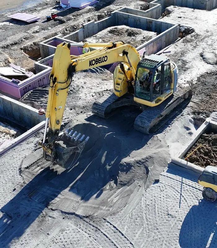 A Kobelco excavator is digging a hole at an excavation site.