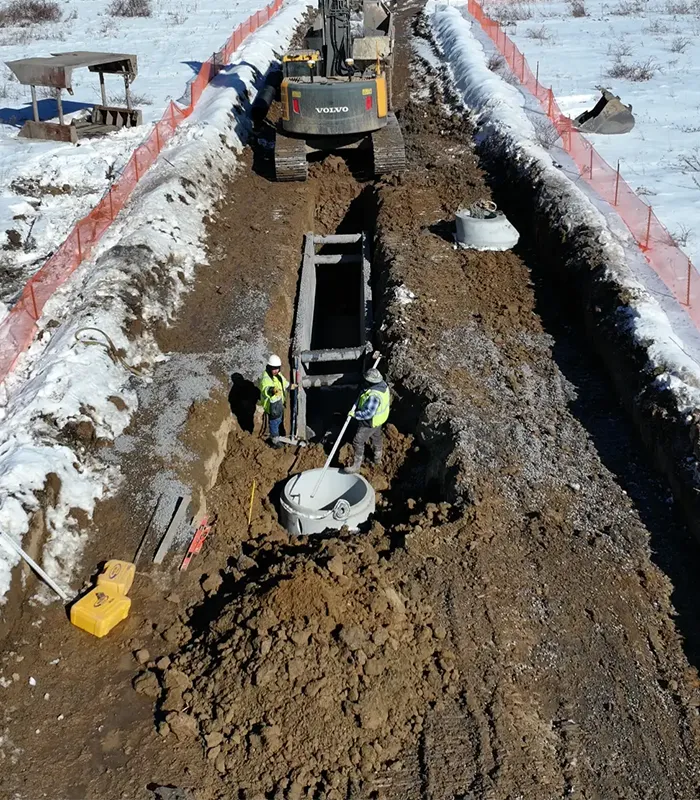 A construction site with workers and machinery surrounded by snow.