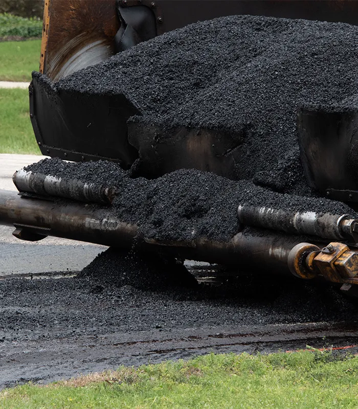 A pile of black asphalt is being transported by a truck.